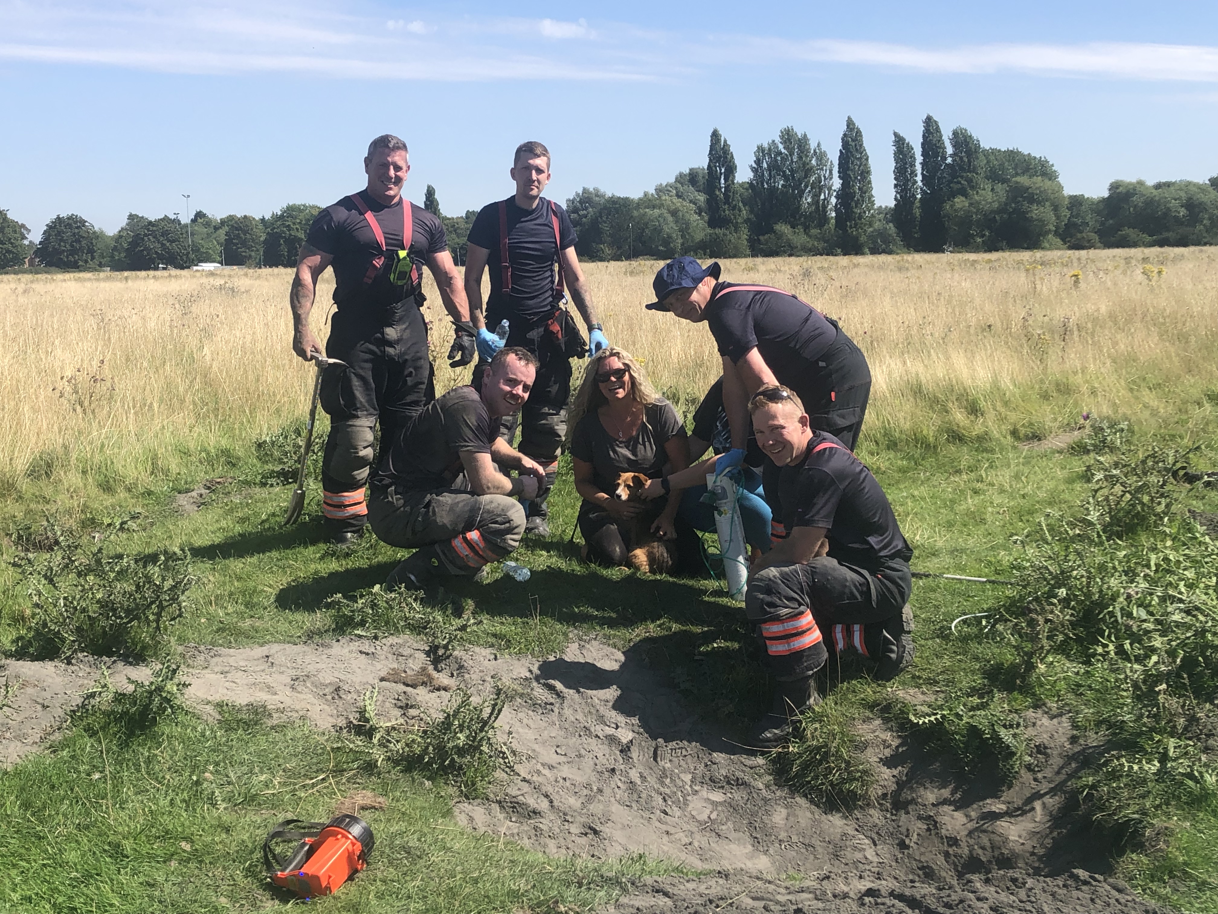Firefighters standing with the dog and its owners.