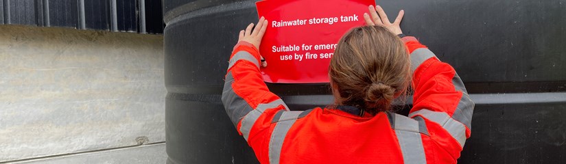 Firefighter placing sticker on tank